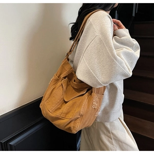 Detail of dark brown canvas shoulder bag with raw fringe edges and retro workwear style