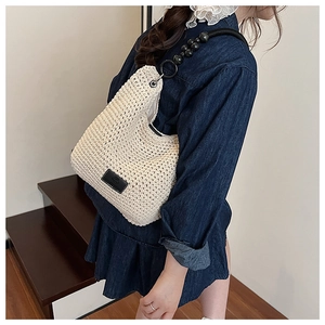 Detail of beige hand-knitted bucket bag showing thick texture and beaded strap