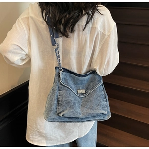 Détail du sac cabas en jean bleu avec fermoir rotatif en métal argenté et bandoulière