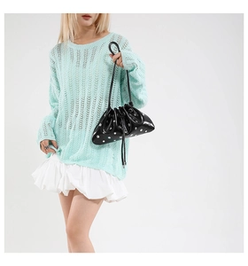 Detail of black metallic rivet drawstring bucket bag paired with mint crochet knit top