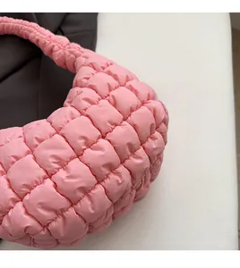 Detalle de la tela acolchada rosa suave y el patrón de cuadros en el bolso de hombro