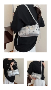 Détail d'un sac porté épaule argenté style Y2K avec rivets et grande boucle décorative