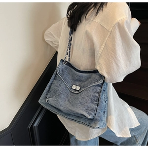 Détail du sac cabas en denim bleu avec fermoir pivotant argenté et bandoulière chaîne