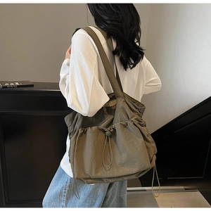 Detailed side view of an olive green large nylon tote bag worn by a model in a studio