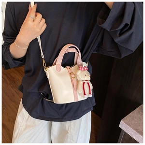 Dettaglio della mini borsa a secchiello con ciondolo orsetto e fiocco di perle in ecopelle crema