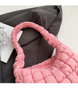 Detalle del bolso acolchado rosa con correa ancha para el hombro y textura suave