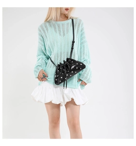 Detail of a black rivet dumpling bag styled with mint green knitwear and white tiered skirt
