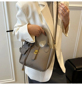 Détail du sac seau gris à grain litchi avec ferrures dorées et breloque en forme de chien