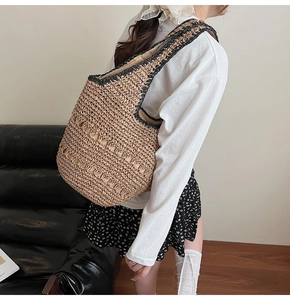 Detailed view of handmade woven straw tote bag with black strap and hollow patterns