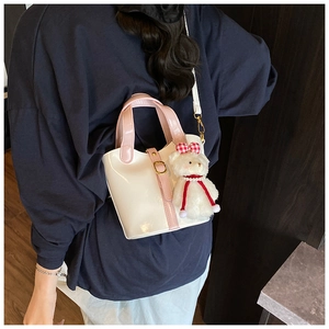 Dettaglio borsa a secchiello bianca lucida con manici rosa e ciondolo orsetto plush