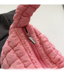Detalle de la cremallera metálica y la tela rosa acolchada del bolso de mano suave