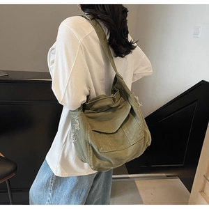 Detail of olive green canvas messenger bag showing distressed edge and wide strap
