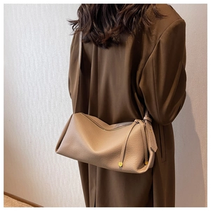 Close-up of a brown pebble leather crossbody bag with a tassel zipper and gold accents