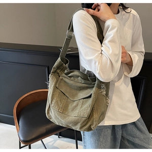 Detail of army green canvas crossbody bag featuring vintage distressed edges and wide strap
