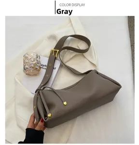 Close-up of grey leather crossbody pillow bag with gold hardware and tassel detail