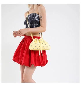 Close-up of bright yellow bucket bag with silver metal rivets and drawstring closure