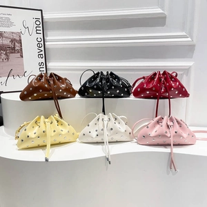 Chic studded drawstring shoulder bags in six vibrant colors displayed on a white stand