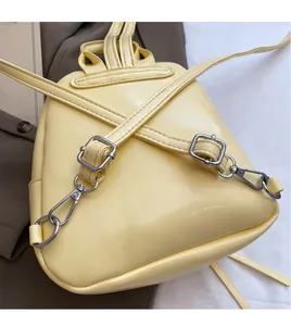 Detail of adjustable slender straps and silver hardware on a yellow PU leather backpack