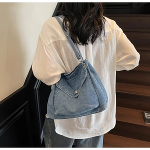 Détail du sac en jean bleu montrant le fermoir argenté et la bandoulière à rivets