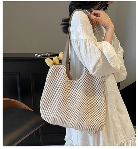 Detail of hand-woven straw tote bag featuring a brown leather strap and hollow mesh texture
