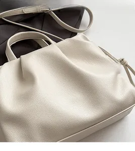 Close-up of creamy white pleated tote with soft lychee grain texture and fine strap