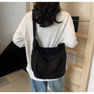 Detail of a large capacity black denim crossbody tote bag with adjustable shoulder strap