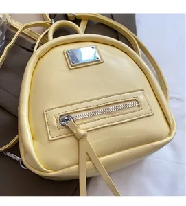 Detail view of bright yellow PU leather backpack with silver plaque and textured fabric