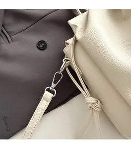 Close-up of silver metal hardware and lychee pattern leather on beige pleated tote bag