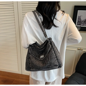 Detail of grey denim hobo bag featuring silver metal buckle and chain leather strap