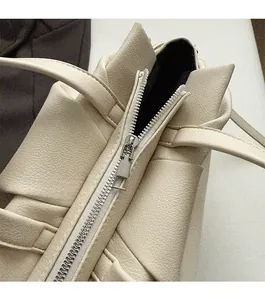 Detail of smooth metal zipper and lychee pattern leather on cream shoulder bag
