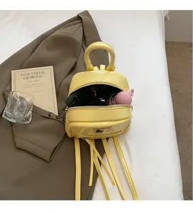 Detail view of yellow PU leather mini backpack showing interior capacity and front pocket
