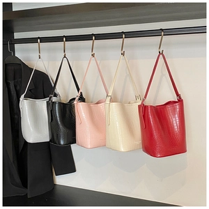Detailed row of five crocodile pattern bucket bags in ivory, black, pink, cream, and red