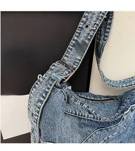 Detail of adjustable wide denim strap with vintage silver buckle on a blue shoulder bag