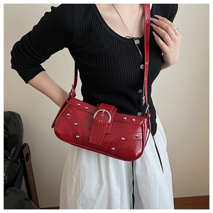 Détail d'un sac sous le bras rouge brillant avec clous argentés et boucle sur modèle