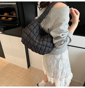 Side view of black quilted cloud bag with pleated texture worn as a shoulder bag