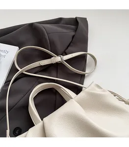 Detail of cream lychee texture leather bucket bag with adjustable shoulder strap and handle