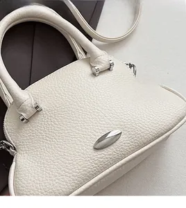 Detail of white lychee pattern leather handbag with silver oval metal accessories