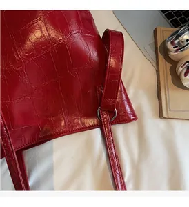 Detailed macro view of red crocodile embossed leather texture with silver metal ring buckle