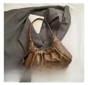 Detail showing vintage brown pleated PU leather texture and gold MKMX metal logo plaque