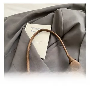 Close-up of a brown leather handbag handle with detailed stitching and soft texture