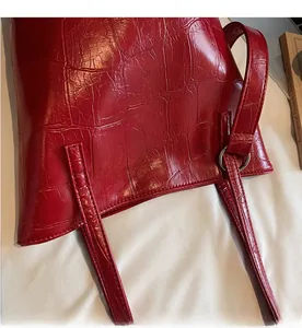 Close-up of red crocodile embossed leather with silver metal ring and stitching detail