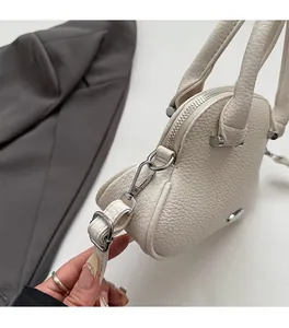 Close-up of premium lychee texture leather and silver metal hardware on a cream tote bag