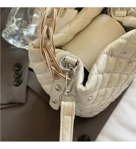 Detail of cream quilted bucket bag showing rhinestone accents and silver lobster clasp
