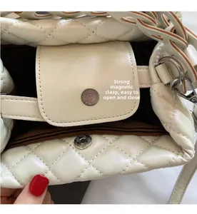 Detail view of strong magnetic closure on cream quilted handbag with striped lining