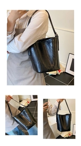 Close-up of a glossy black crocodile pattern bucket bag with versatile shoulder straps