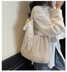 Detail of beige woven tote bag featuring hollow mesh texture and a white lace bow accent
