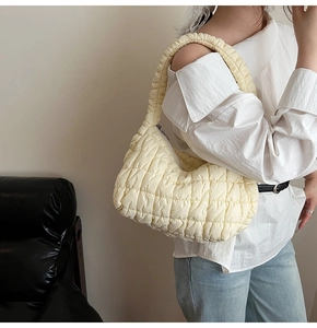 Detail of beige quilted dumpling bag with crescent shape and soft texture