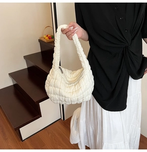 Detalle del bolso nube acolchado blanco con textura suave y cierre de cremallera plateado
