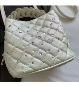 Detail of pearlescent quilted bucket bag with rhinestones and woven handle