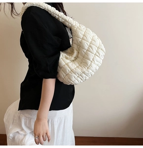 Detail of white quilted cloud bag featuring elastic pleated shoulder strap and soft texture